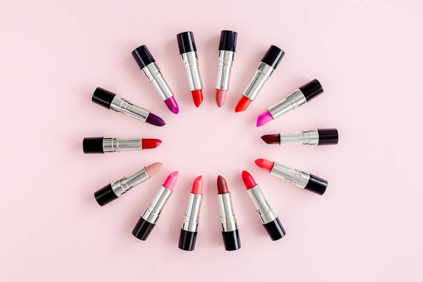 Set of color lipsticks on pink background. Professional decorative cosmetics, product pomade. Flat composition beauty, fashion. flat lay, top view - 写真・画像