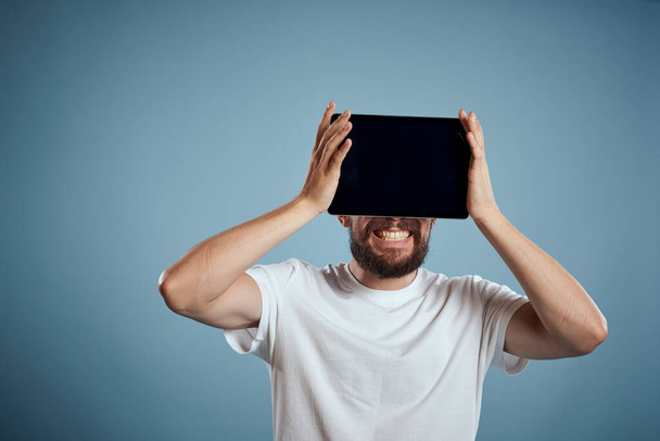 homem com tablet perto do rosto no fundo azul corte vista toque monitor novas tecnologias Copiar espaço - Foto, Imagem