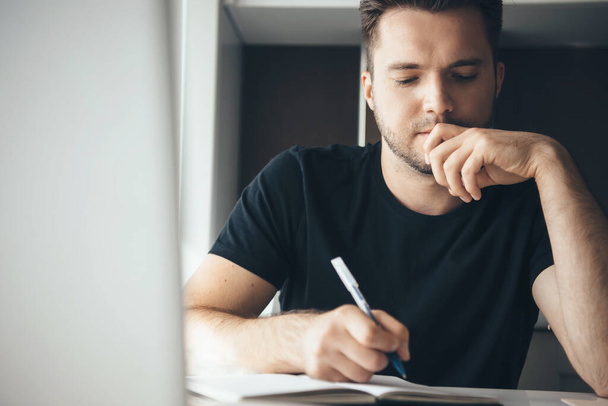 Düşünceli beyaz adam evde çalışırken işe odaklanmış bir şeyler yazıyor. - Fotoğraf, Görsel