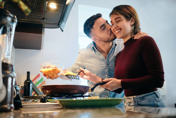 Husband And Wife Cooking Together Hugging And Kissing - Foto, Imagen