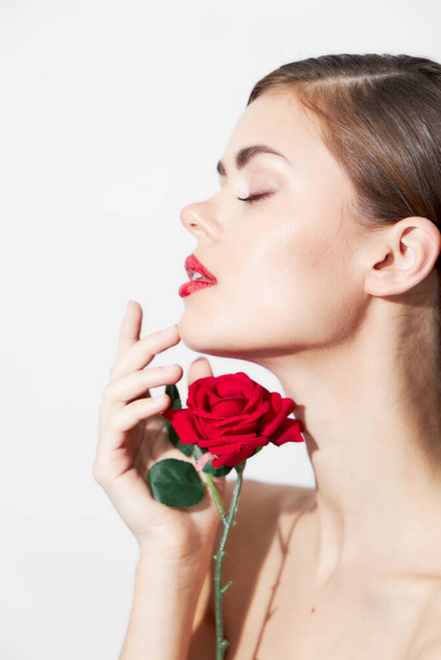 Woman with rose sniffs a flower with her eyes closed bright makeup  - Фото, изображение