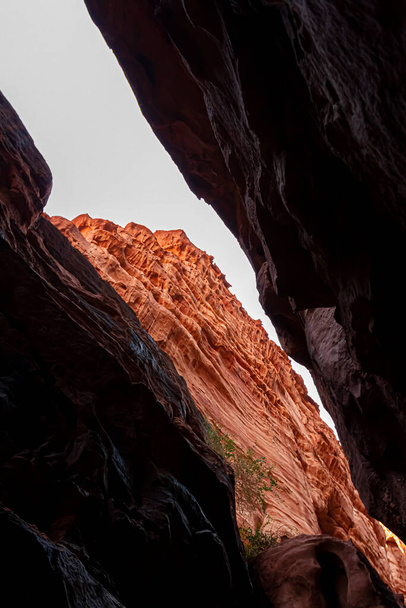 ハザーリ峡谷、ヨルダンのワディ・ラムにある巨大な赤い砂岩の岩の間の狭い通路の写真。画像は峡谷の上の開口部を通って外側を示しています - 写真・画像