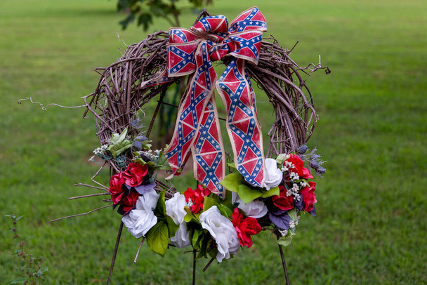 Στεφάνι από μπλε, λευκά και κόκκινα λουλούδια με κορδέλες με θέμα τη σημαία της Συνομοσπονδίας. Αυτό το στεφάνι τοποθετήθηκε στο Point Lookout Prisoner of war camp όπου 3384 Ομόσπονδοι αιχμάλωτοι πέθαναν λόγω κακών συνθηκών. - Φωτογραφία, εικόνα