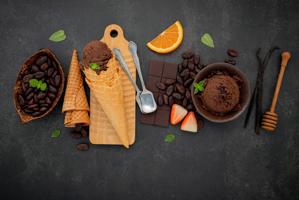 Sapori di gelato al cioccolato in ciotola con cioccolato fondente e pennini di cacao montati su fondo pietra scura . - Foto, immagini