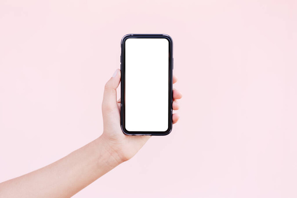 Detailní záběr ruky držící smartphone s maketou. Pastel růžové pozadí. - Fotografie, Obrázek