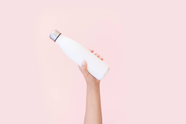 Kadın elinin yeniden kullanılabilir, çelik eko termodinamik su şişesi beyaz, arka planda izole edilmiş, pembe renkli. Plastikten uzak dur. Sıfır kayıp. Çevre kavramı. - Fotoğraf, Görsel