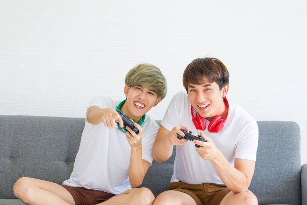 Felice asiatici omosessuali uomini o coppie gay stanno giocando videogiochi sul divano insieme. Concetto di orgoglio LGBTQ. - Foto, immagini