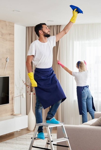 Profesionální úklidový tým uklízí obývací pokoj v moderním bytě - Fotografie, Obrázek