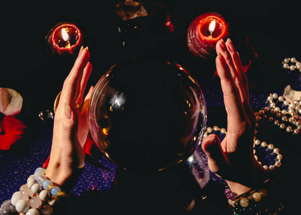Fortuneteller's hand on a glass ball, crystal orb. Prediction of the future. Mystic interior. Occult symbols - Photo, Image
