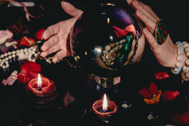 Fortuneteller's hand on a glass ball, crystal orb. Prediction of the future. Mystic interior. Occult symbols - Photo, Image