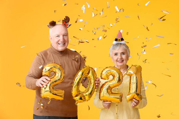 Coppia anziana con figura 2021 sullo sfondo a colori. Festeggiamenti di Capodanno - Foto, immagini