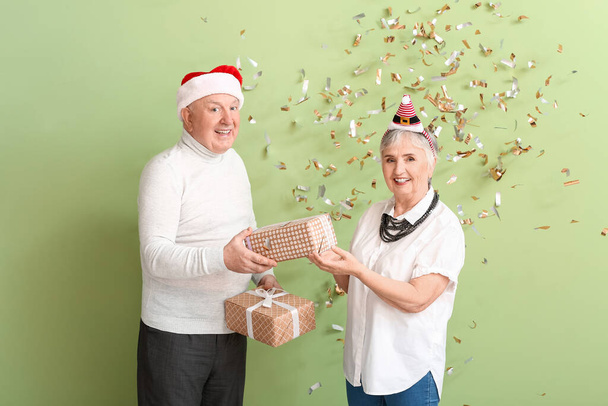 Elderly couple with Christmas gifts on color background - Photo, Image