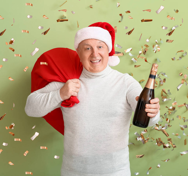 Oudere man met champagne vieren Kerstmis op kleur achtergrond - Foto, afbeelding