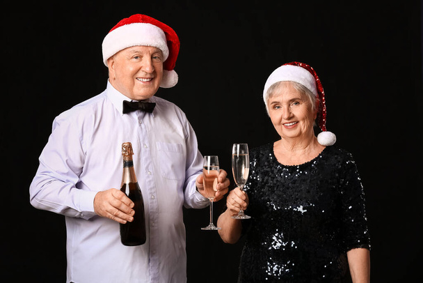 Idős pár pezsgővel ünneplő karácsony sötét háttér - Fotó, kép