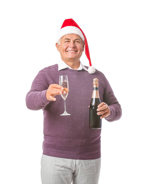 Oudere man in Santa hoed en met champagne op witte achtergrond - Foto, afbeelding