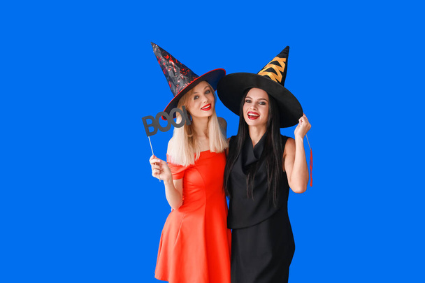 Mooie jonge vrouwen verkleed als heksen op kleur achtergrond. Halloween viering - Foto, afbeelding