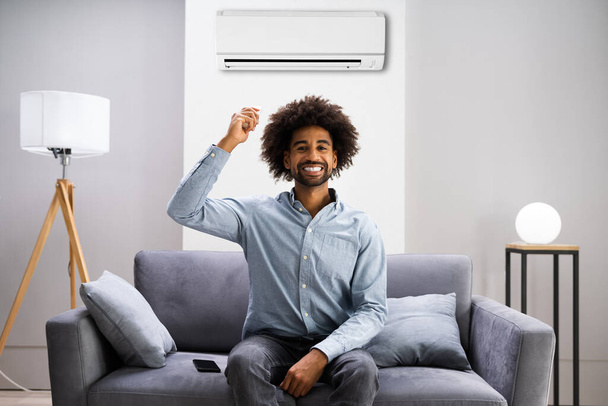 African American Using Air Conditioning To Cool Home - Photo, image