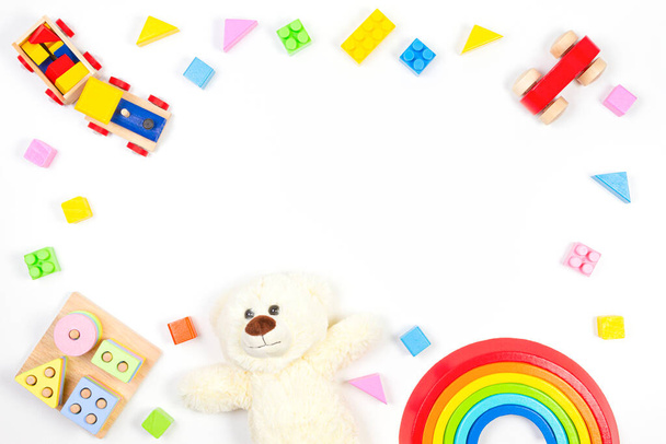 Baby kids speelgoed frame op witte achtergrond met teddybeer en kleurrijke houten speelgoed. Bovenaanzicht, vlak lay - Foto, afbeelding