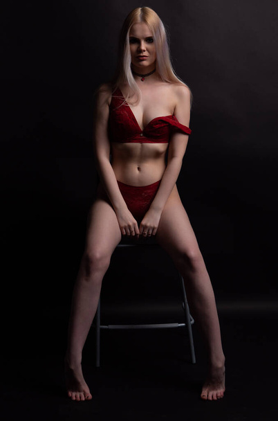 Sexy blonde woman in Lacy red underwear erotic sitting on a chair looking at the camera - Fotografie, Obrázek