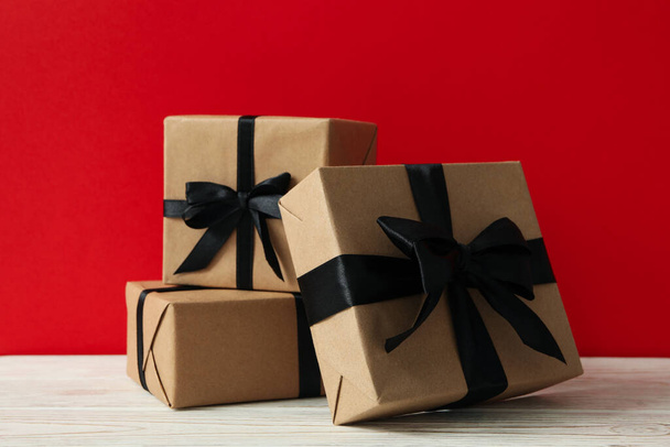 Gift boxes on wooden table against red background - Photo, Image