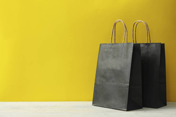 Paper bags on wooden table against yellow background - Foto, imagen