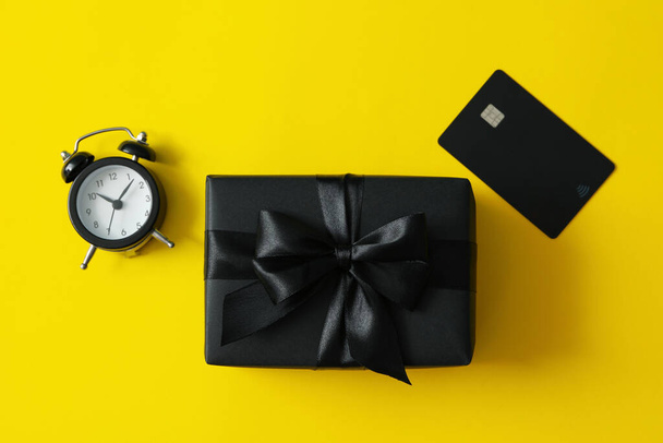 Gift box, alarm clock and card on yellow background - Фото, зображення