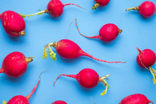 Red ripe radishes on blue background - Foto, afbeelding