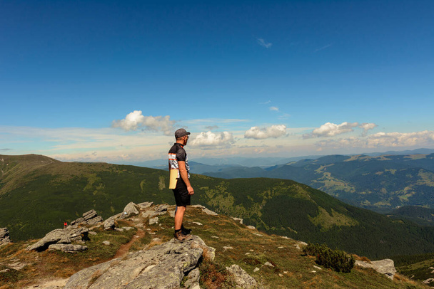 reiziger, toerist, reiziger staat op de top van een klif en geniet van een zonnige dag en een uitzicht op de pittoreske Karpaten. 2020 - Foto, afbeelding