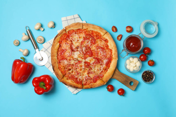Tasty pizza and ingredients on blue background - Photo, Image
