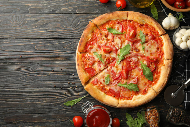 Lezzetli pizza ve ahşap arka planda malzemeler - Fotoğraf, Görsel