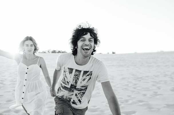 Cheerful couple in love running on the beach and enjoying their vacation - Fotografie, Obrázek