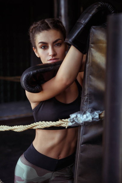 Beautiful slim sexy sportswoman in the ring and the gym in boxing gloves. - Photo, image