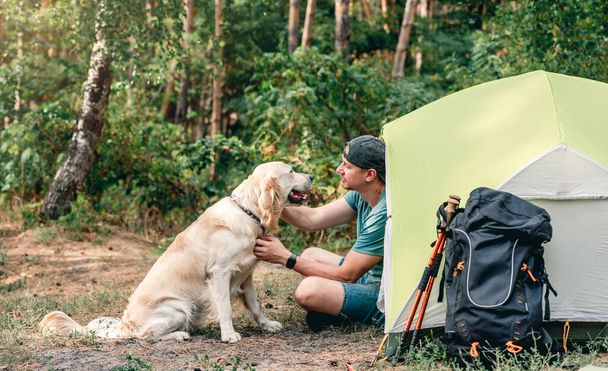 Man with dog next to tent - 写真・画像