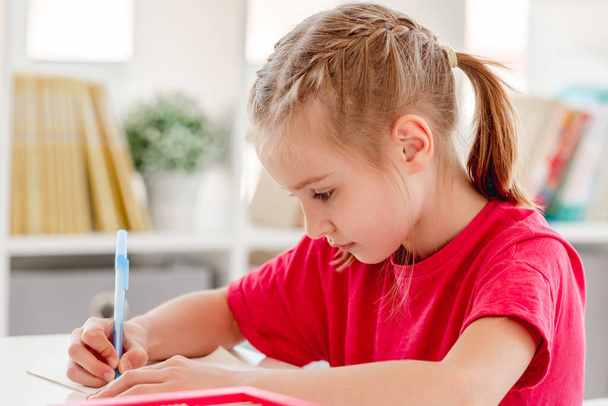 Little girl writing in notebook with pen - Photo, image
