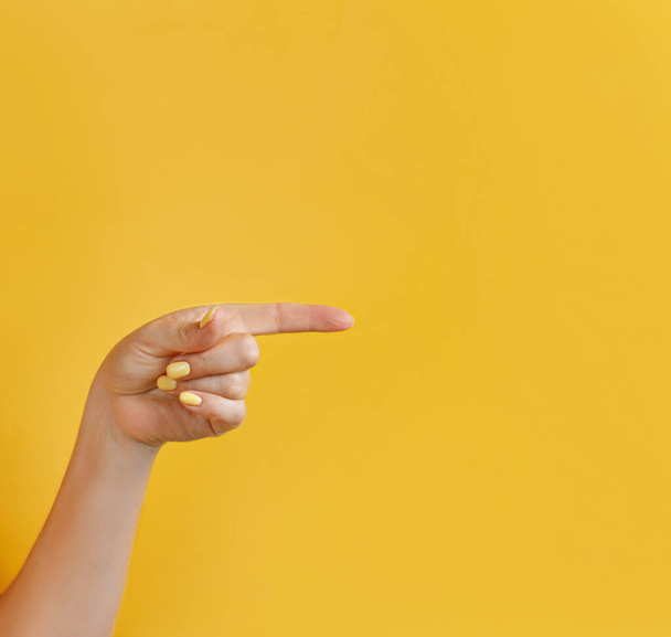 Close up of female hand pointing away on yellow  background - Фото, зображення