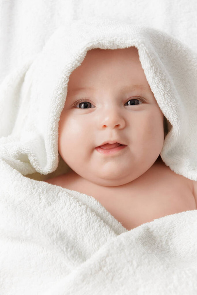 Happy smiling baby in a towel after bathing - Fotó, kép