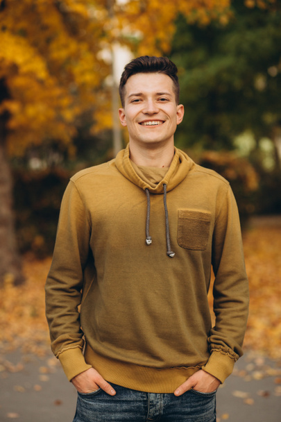 Portrét pohledného chlapa usmívajícího se v podzimním parku - Fotografie, Obrázek