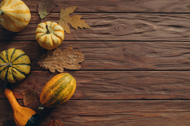 Koncept Díkůvzdání. Místní produkce dýně, podzimní suchý dub a javorové listy pro dekoraci na dřevěné texturované stůl.  - Fotografie, Obrázek