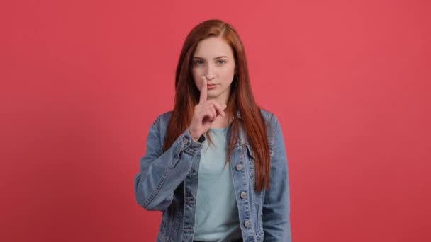 Mädchen zeigt mit Finger ruhig zu sein, isoliert auf rotem Hintergrund. - Filmmaterial, Video