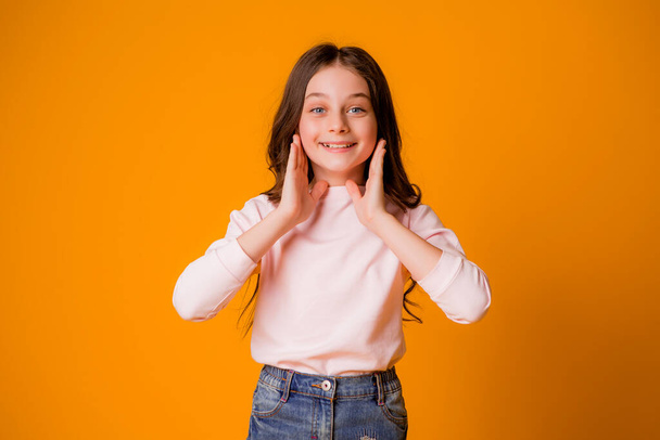 cute little girl in studio over orange background - Foto, afbeelding