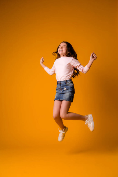 roztomilý holčička ve studiu přes oranžové pozadí - Fotografie, Obrázek