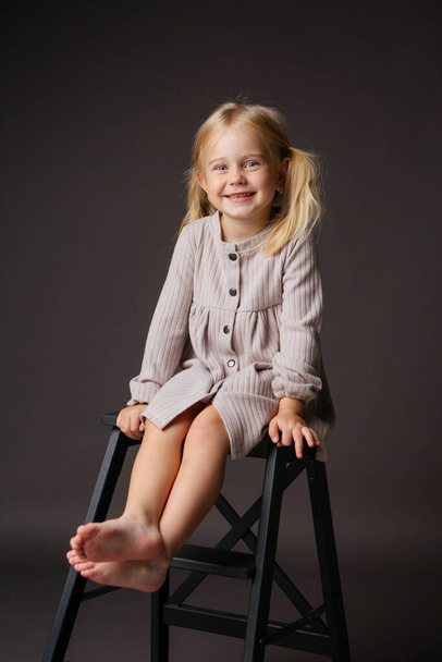 aranyos kislány szürke ruha a stúdióban  - Fotó, kép