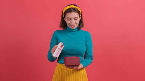 Portret van gelukkige vrouw opening gift box over rode achtergrond. - Video