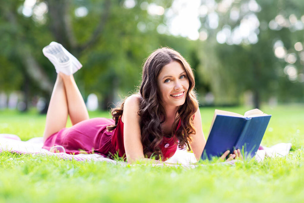 happy smiling woman reading book at summer park - Foto, Imagen