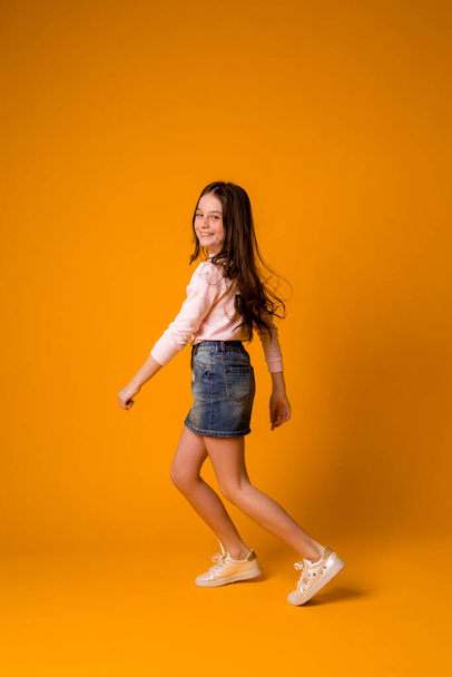 cute little girl in studio over orange background - Fotó, kép