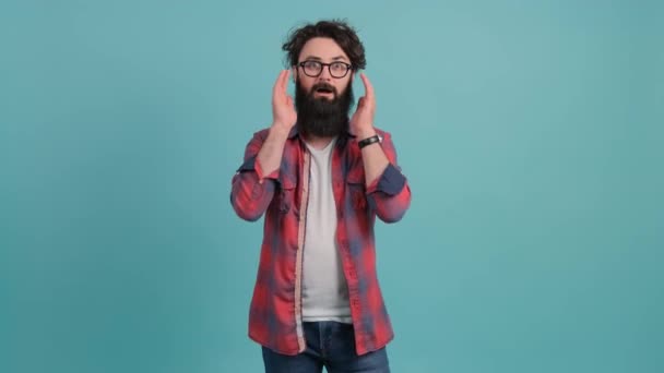 Jonge man met baard met verbazing en verbluffende uitdrukking met handen op het gezicht. - Video