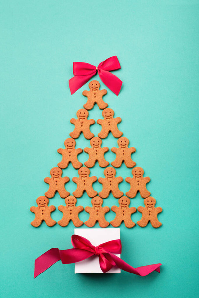Christmas tree made from homemade gingerbread cookies and gift on blue mint background. Holiday, celebration, cooking concept. New year and christmas postcard. Top view, Flat lay, Copy space. - Photo, Image