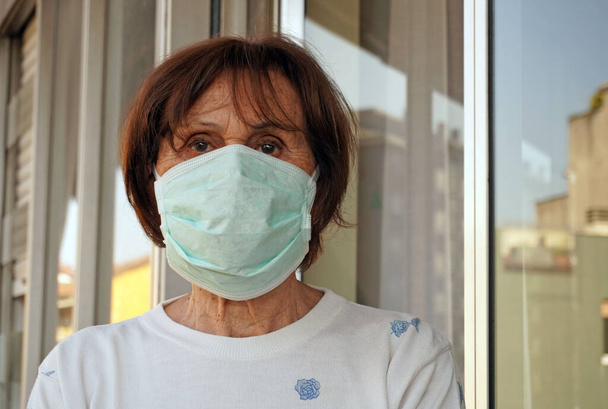 Eurooppa, Italia, Milano - Pandemiatilanteet n-kovalevy19 Coronavirus - Karanteenissa oleva 70-vuotias nainen, joka suorittaa erilaisia toimintoja kotona naamion kanssa - Valokuva, kuva