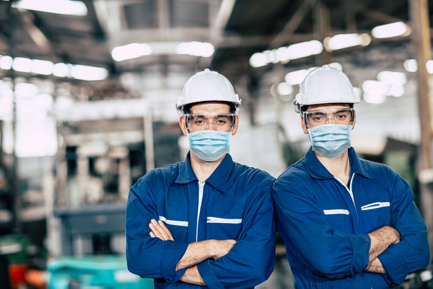 Portrait travailleur portant un écran facial ou un masque facial jetable pendant le travail de l'équipe de service en usine pour prévenir le coronavirus (Covid-19) ou la pollution de la poussière de l'air dans l'usine. - Photo, image