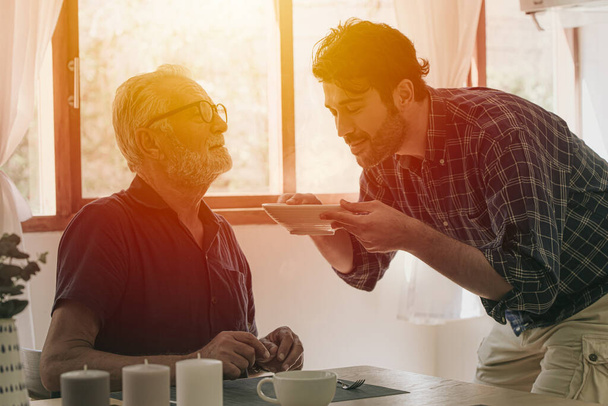 Щасливий старший літній чоловік насолоджується приготуванням їжі з сім'єю на кухні, залишається домашнім дозвіллям і способом життя людей
 - Фото, зображення